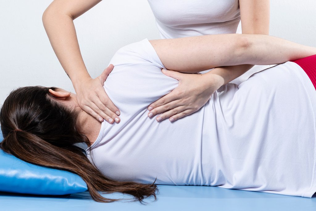 Woman having chiropractic back adjustment. Osteopathy, Alternative medicine, pain relief concept. Physiotherapy, sport injury rehabilitation